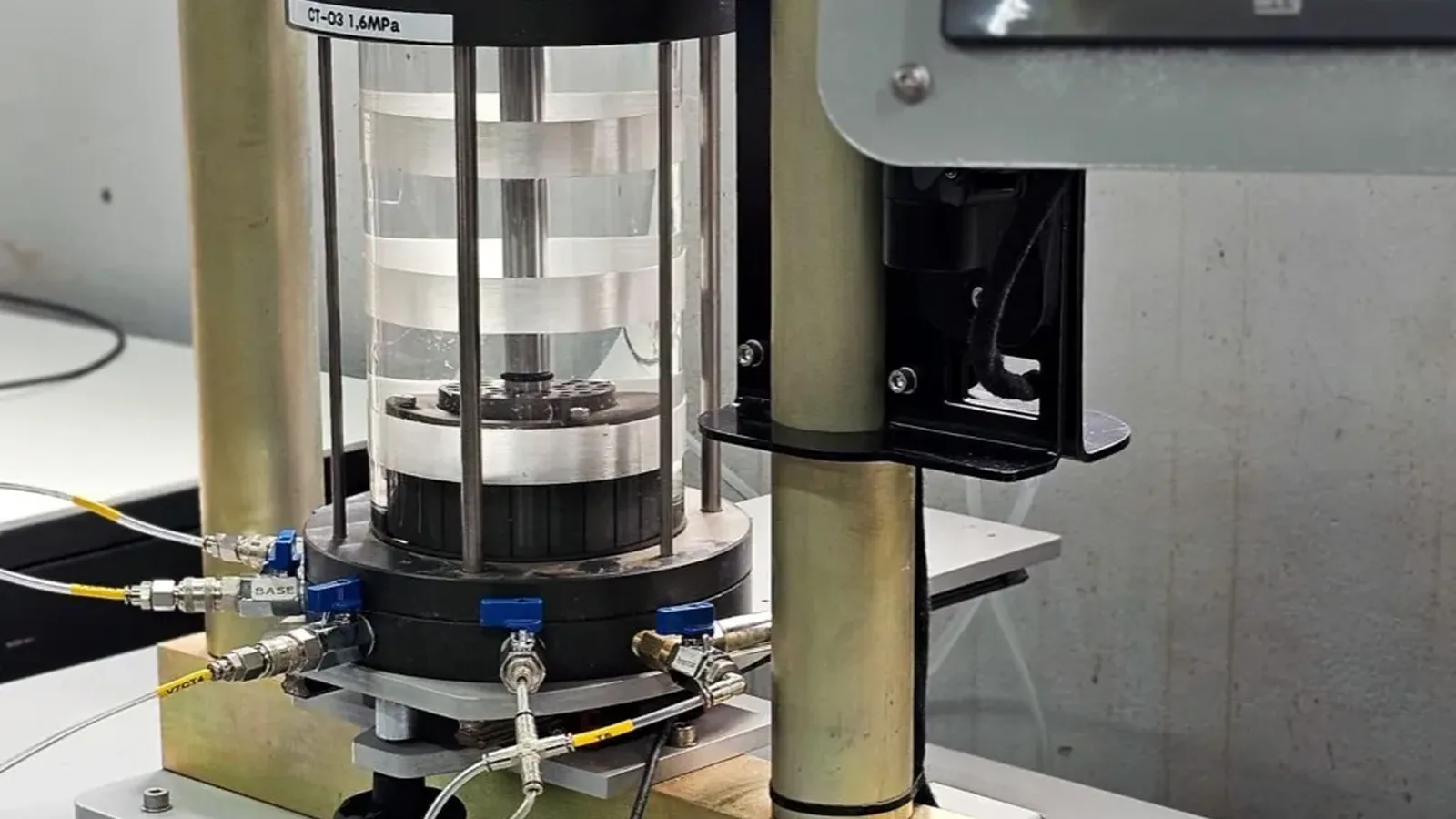 Célula triaxial montada na prensa, com painel de pressões e console de aquisição no laboratório da Damasco Penna